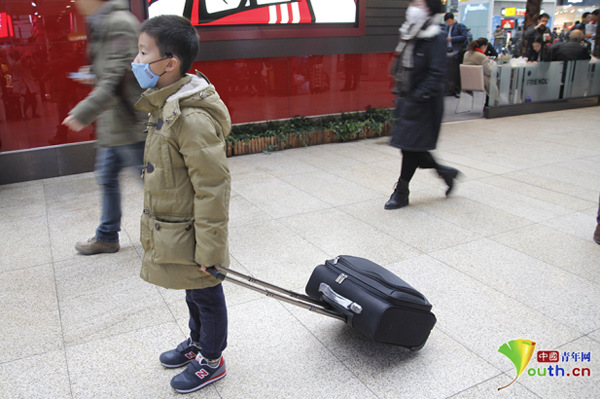 A boy wears a protective mask as he waits to embark on a train leaving Beijing as heavy smog blankets the city, Dec 8, 2016. (Photo/Youth.cn)