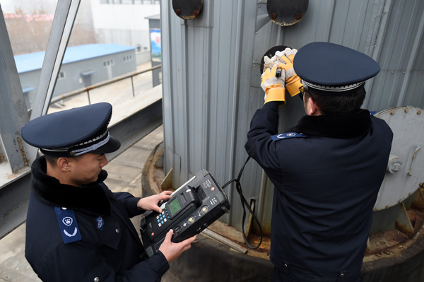 Two environmental protection officers check the level of sulfur dioxide emissions at a heat-supply plant in Beijing, Nov 18, 2016. (Photo/Xinhua)