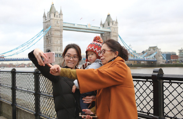Three Chinese tourists pose for a selfie next to the River Thames in London. (Photo/chinadaily.com.cn)