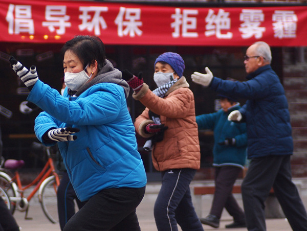 People exercise in Linfen, Shanxi province, on Tuesday morning. The slogan on the red banner reads,Promote environmental protection and say 'No' to smog.Xu Yin / For China Daily