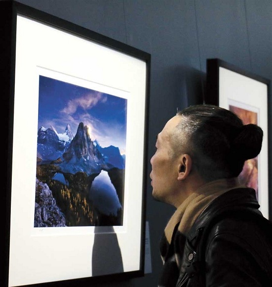 A visitor looks at a photograph on display at a landscape photo show at Shanghai World Financial Center.(Photo/Shanghai Daily)