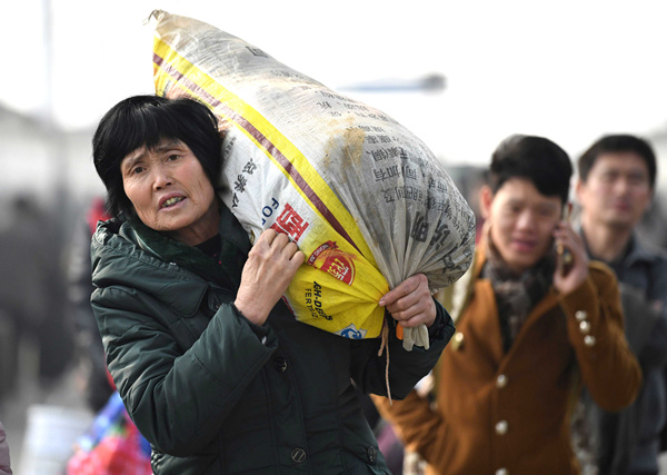 A passenger carries her luggage as she heads home for Lunar New Year celebrations at a railway station in Bozhou, Anhui province, on Thursday. (Photo by Liu Qinli/China Daily)