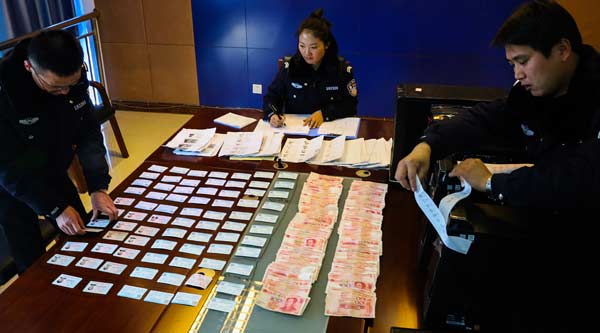 Railway police in Lhasa, capital of the Tibet autonomous region, sort train tickets, cash and computers seized during crackdown on digital scalpers. (Photo provided to China Daily)