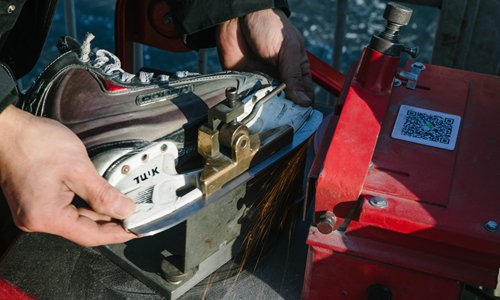 Zhao uses a blade sharpener to sharpen his teammate's skates. (Photo: Li Hao/GT)