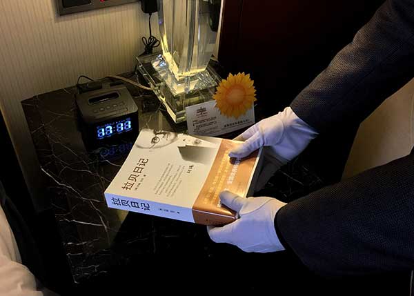 An employee of a hotel in Taizhou, Zhejiang province, puts The Good Man of Nanking: The Diaries of John Rabe in a guest room on Friday.(Photo provided to China Daily)