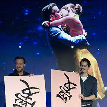 Ryan Gosling (left), the lead actor, alongside Damien Chazelle, the director, write the Chinese character ai (love) during their Beijing promotional tour on Tuesday.(Photo by Feng Yongbin/China Daily)