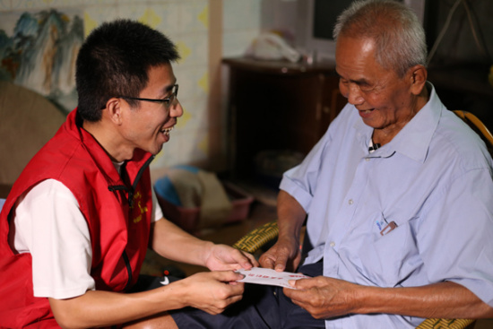 Volunteer Chen Shangyuan visits Huang Tanghua, a veteran of WWII, July 9, 2015. (Photo provided to chinadaily.com.cn)