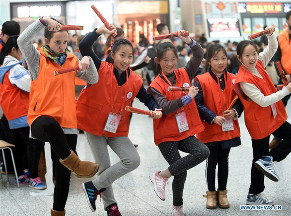 Rachel (1st L) from Britain performs the Monkey King with young volunteers during a break at the East Railway Station of Hangzhou, capital of east China's Zhejiang Province, Jan. 23, 2017. Five foreign volunteers worked at the railway station to offer help to passengers who rush home for family reunion during the Spring Festival. (Xinhua/Wang Dingchang)