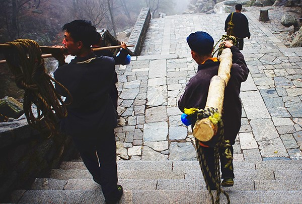 Porters carry heavy poles on Mount Tai in Shandong province. (CHE HONGGANG/CHINA DAILY)
