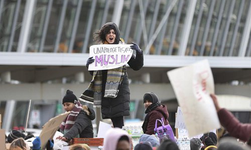 People hold posters during a protest against President Donald Trump's executive order banning entry of citizens from seven Muslim-majority countries, outside the Terminal 4 at John F. Kennedy International Airport in New York, the United States, Jan. 29, 2017. (Photo/Xinhua)
