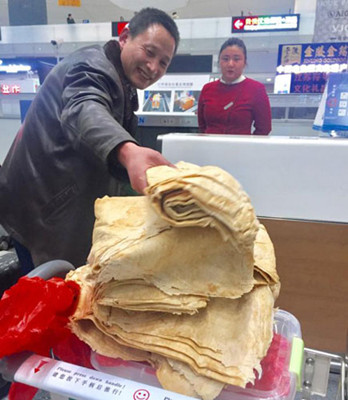 A man checks in with a pile of pancake and pickles made by his mother at Lukou international airport in Nanjing, East China's Jiangsu province, on Feb. 2, 2017. (Screenshot Photo)