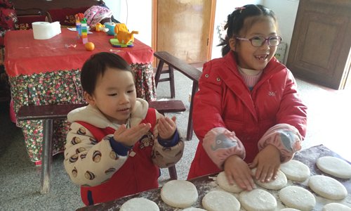Children help their parents make traditional rice cakes before the eve of Spring Festival. Photo: Huang Jingjing/GT