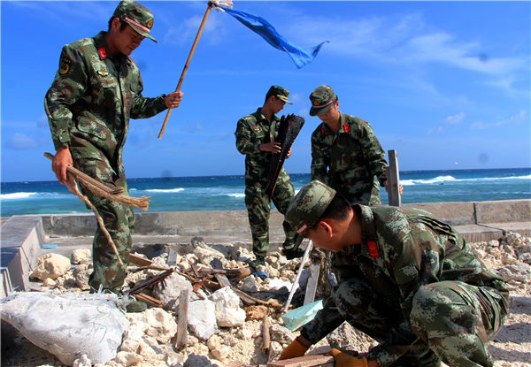 Frontier guards from the Chinese People's Armed Police collect seaborne debris on a beach on Yongxing Island, Hainan province, for treatment at the island's recycling plant. (Photo by LI MINGJIAN/CHINIA DAILY)