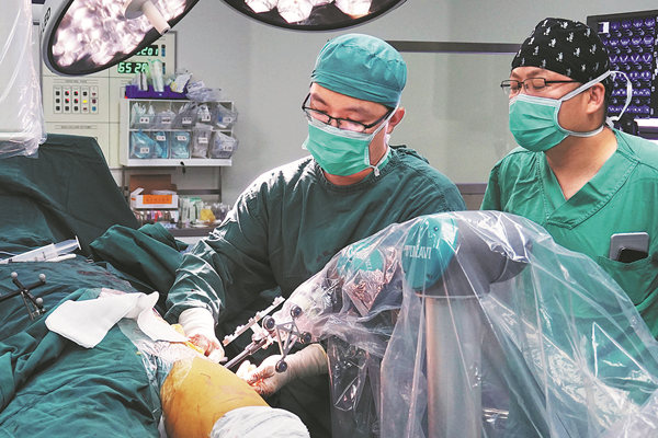 A doctor uses Phecda, a surgical robot developed by Tinavi, to do orthopedic surgery in Beijing Jishuitan Hospital in 2016. PROVIDEDTOCHINADAILY