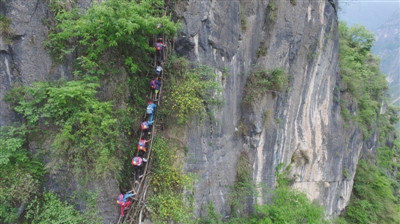 Children climb up a cliff on a vine ladder to an isolated village on the top of a mountain in Liangshan Yi autonomous prefecture, Southwest China's Sichuan province, on May 14, 2016. (Photo/Beijing News)