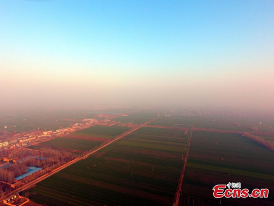 An aerial picture shows a smog storm rolling across clear skies, 500 meters above the ground, in Liaocheng City, East China��s Shandong Province, Jan. 2, 2017. (Photo: China News Service/Zhao Yuguo)