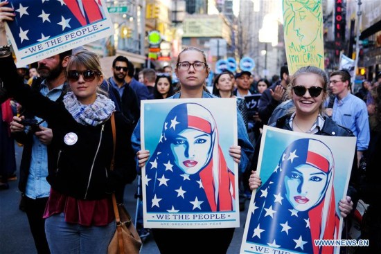 Protesters hold placards to demonstrate against U.S. President Donald Trump's immigration policy at Times Square in New York City, the United States, on Feb. 19, 2017. (Xinhua/Yuan Yue)