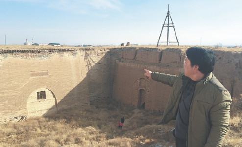 Yang Guoxing, a farmer who helps protect the Great Wall, points to inscriptions on a Great Wall entrance in Tongxin county, Ningxia Hui automous region, earlier this month. (Photo/Xinhua)