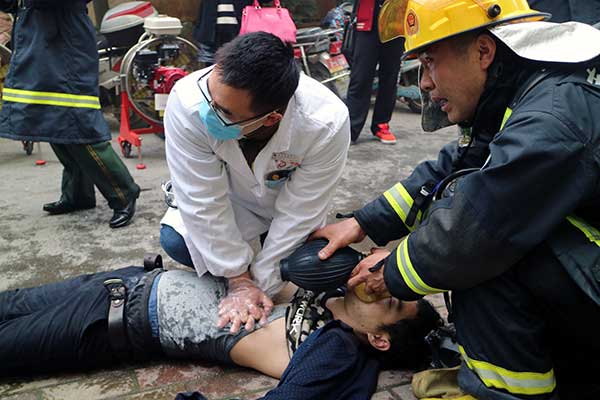 Emergency workers treat a victim after arriving at the scene of a fire at a high-rise in Nanchang, Jiangxi province, on Saturday.(Photo provided to China Daily)