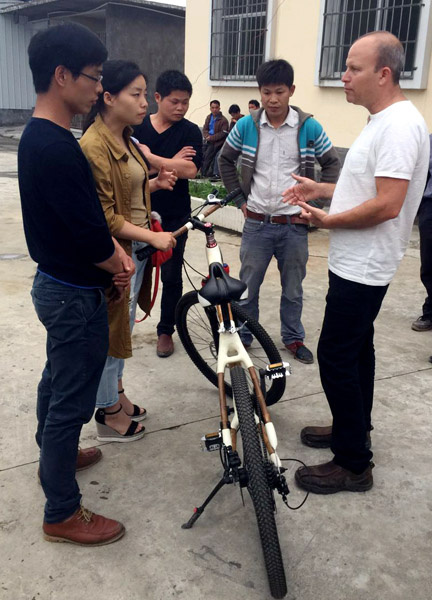 Tan Jiangyong (left) talks with a foreign buyer about bamboo bikes.Provided To China Daily