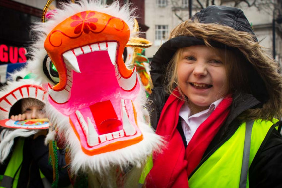 A little girl takes a photo with a Chinese dragon figure at the Chinese New Year parade in London, Jan 29, 2017. (Photo by Lu Yufan)