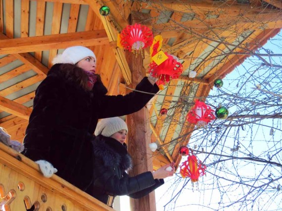 Two Russian girls decorate a tree with Chinese red lanterns. (Photo by Krasilnokova Ekaterina and Zolotukhina Anastasiia)
