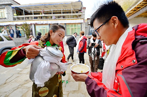 Dekyi, a Tibetan resident, serves barley wine to a tourist who opted for a home stay at her house in Lhasa, Tibet autonomous region, in November. (Photo by Liu Dongjun/Xinhua)
