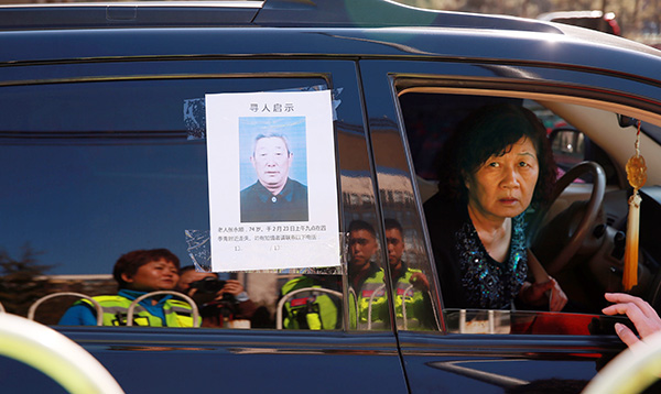 A relative conducts a search for a missing senior, whose details are posted on her car window. (Photo by Zou Hong/China Daily)