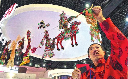 A craftsman from Huanxian county, Gansu province, shows puppets at a cultural expo. (Photo by Li Shengli/China Daily)