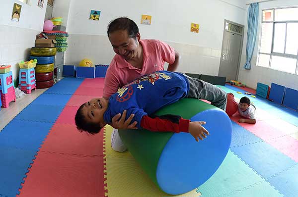 Special education teacher Dai Jianrong helps a disabled child complete sensory integration training in Kunming, Yunnan province. (Photo/Xinhua)