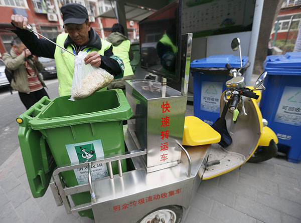 A sanitation worker collects kitchen waste in a residential area in Beijing's Chaoyang district on Wednesday.Cao Boyuan / For China Daily