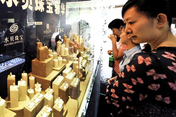 Customers examine jewelry in Shuibei village, Guangdong province, once a leading production center in China. (Photo/Xinhua)