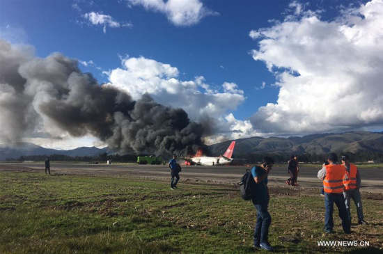 Image taken with a mobile device shows people standing in front of a Peruvian Airlines passenger plane on fire, at the Francisco Carle Airport in Jauja, Peru, on March 28, 2017. (Xinhua/Carlos Fernandez)