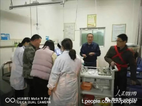 Xu Yilong (right, first) carries out emergency procedure while carrying his daughter on his back at Yushan People's Hospital in Jiangxi province on March 25. (Photo from t.people.com.cn)