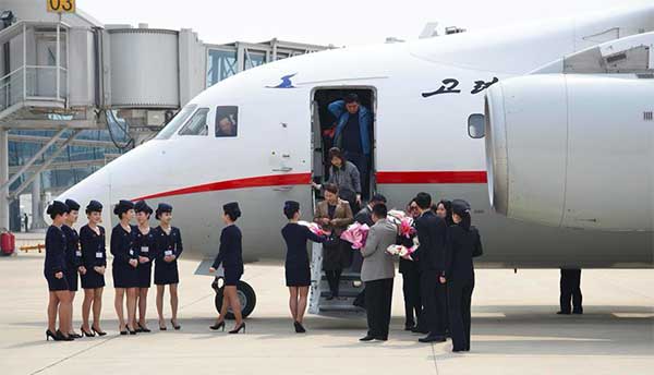 Air Koryo crew members present bouquets to passengers at the Pyongyang Sunan International Airport on March 28. (Photo/Xinhua)