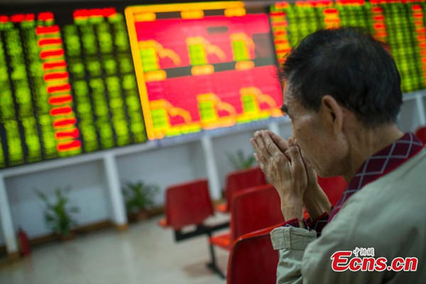 Investors look at an electronic board showing stock information at a brokerage house in Taiyuan, north China's Shanxi Province, Jan. 4, 2016. Trading on the first day of the year closed earlier than expected, as a 7 percent slump triggered circuit breaker mechanism to halt the market. (Photo: China News Service/Wei Liang)