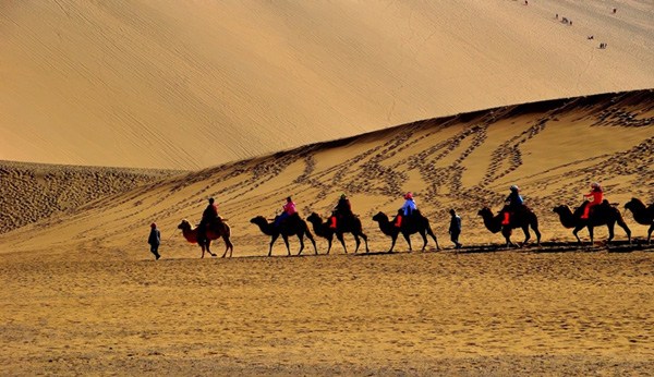 Tourists ride camels on the Mingsha Sand Dunes during a visit to Crescent Moon Spring on the outskirts of Dunhuang county of northwest China's Gansu province. (Photo/China Daily)