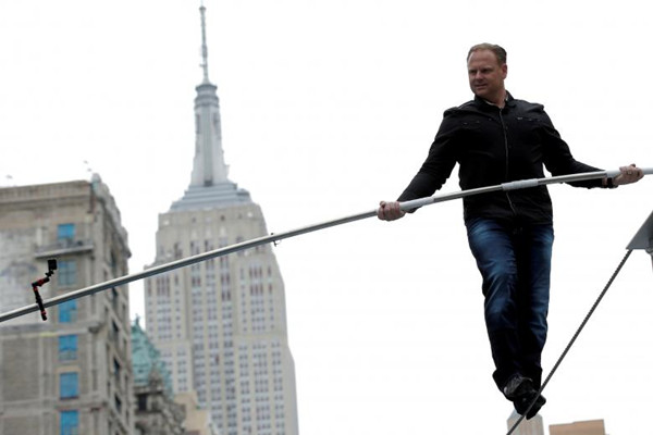 File Photo: Aerialist Nik Wallenda walks a tightrope during a promotional event in midtown Manhattan, with the Empire State Building behind him, in New York City, U.S., May 17, 2016 .(Photo/Agencies)