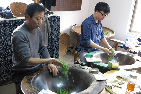 Fan Shenghua (left) teaches his apprentice the traditional panning skill. (Photo by Wu Yuanfeng/Shi Xiaofeng/China Daily)