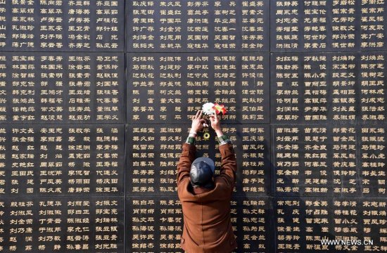 A citizen pastes paper flowers beside the name of the relative killed in the 1976 Tangshan earthquake in front of a memorial wall in Tangshan, north China's Hebei Province, April 3, 2017. (Xinhua/Mu Yu)