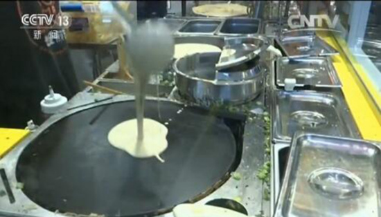 A traditional jianbing starts with batter ladled onto a round cast-iron griddle.(Photo/CCTV)