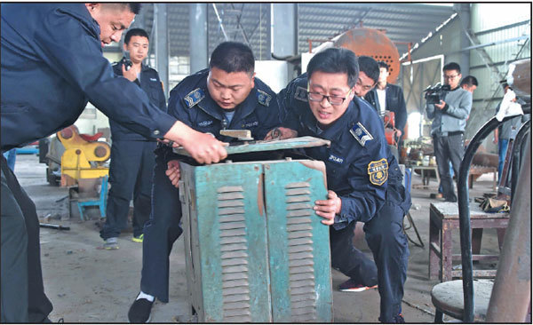 Environmental protection and urban patrol officers seize equipment at a boiler factory of Shandong Lyujie Green Technology Co in Jinan, Shandong province, on Monday. The company was shut down after environmental protection inspectors were locked in a section of the plant for more than an hour on Sunday.Xu Suhui / Xinhua