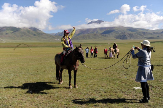 Tourists visit the Bayan Bulag grassland in Hejing County, northwest China's Xinjiang Uygur Autonomous Region, Aug. 12, 2016. (Xinhua/Wei Hai) 