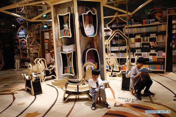 An adult read books with a child at Zhongshuge bookshop in Hangzhou, capital of east China's Zhejiang Province, April 21, 2017. The bookshop with the elements of the amusement park, such as roller coasters, hot air balloons, the merry go round, and attracted many children and their family members. (Xinhua/Zhang Cheng)