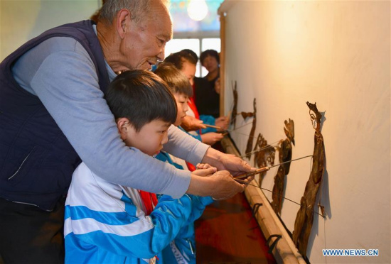 Students try the shadow puppet guided by artist Zhang Jin at a primary school affiliated to the No. 2 middle school in Shahe city, north China's Hebei Province, April 19, 2017. (Xinhua/Zhu Xudong)