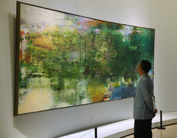 Wang Yancheng shows his abstract oil paintings at a solo exhibition at the National Art Museum of China.(Photo by Jiang Dong/China Daily)