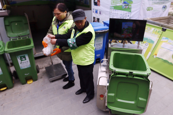 Staff weigh trash prior to handing out credit coupons. (Photo by Cao Boyuan/For China Daily)