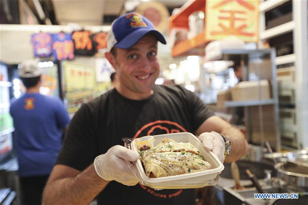 Brian Goldberg shows a Jianbing at the kiosk of Mr. Bing in UrbanSpace food court in New York, the United States, April 17, 2017. (Photo/Xinhua)