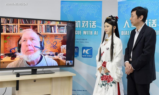 Chen Xiaoping (R), director of a robot research and development team, and Jia Jia, an interactive robot that looks like a real Chinese young woman in traditional outfit, talk through internet with Kevin Kelly on screen, founding executive editor of Wired magazine, in Hefei, capital of east China's Anhui Province, April 24, 2017. (Xinhua/Guo Chen) 