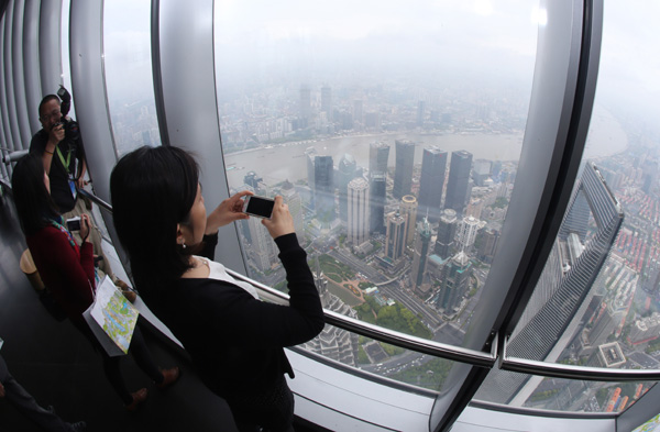 Visitors take photos from the observation deck on the 118th floor of Shanghai Tower on Wednesday, at a height of 546 meters above the ground.(Shao Jianping / For China Daily)